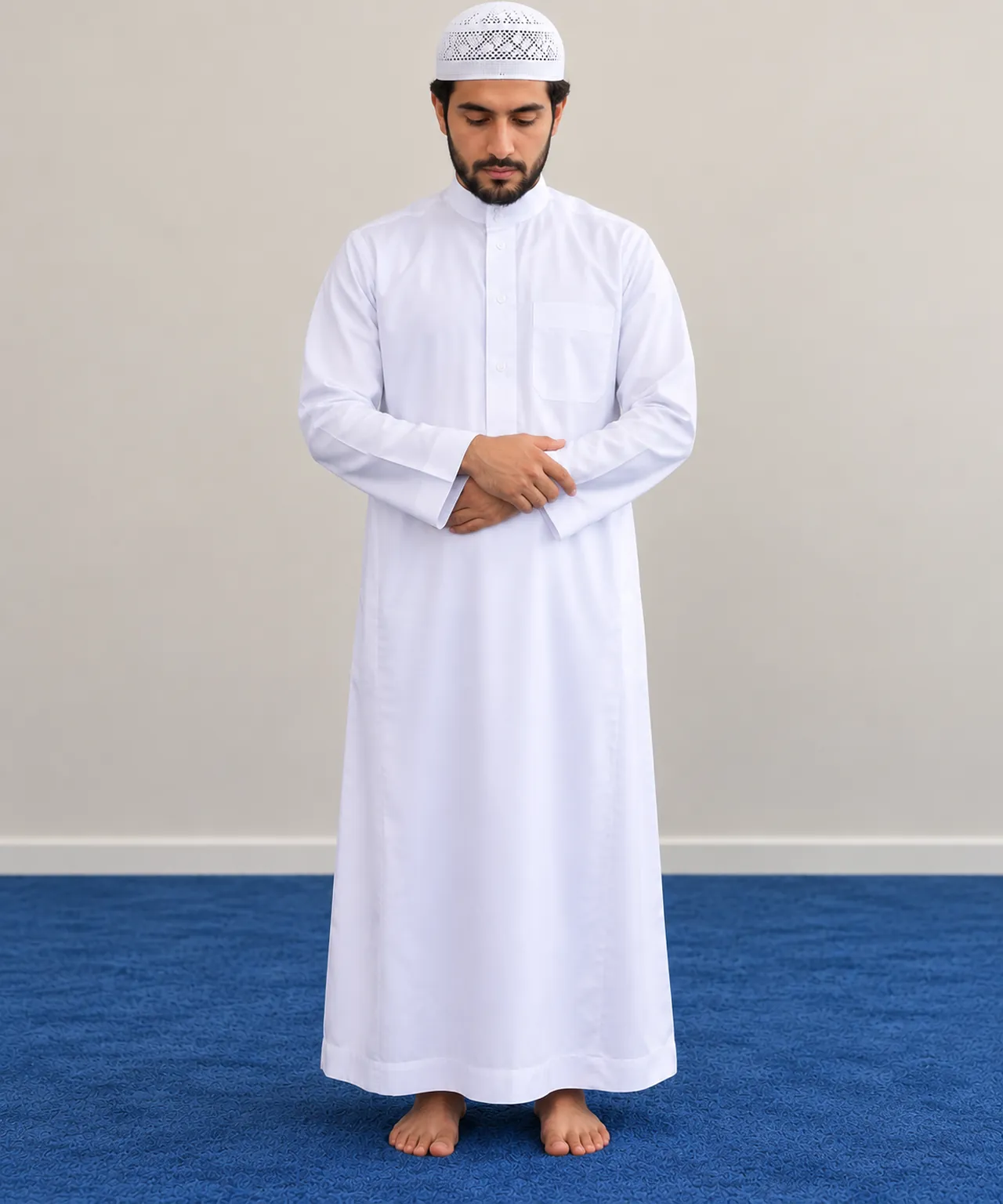 Homme debout, main droite posée sur la main gauche au-dessus du ventre, regard baissé.